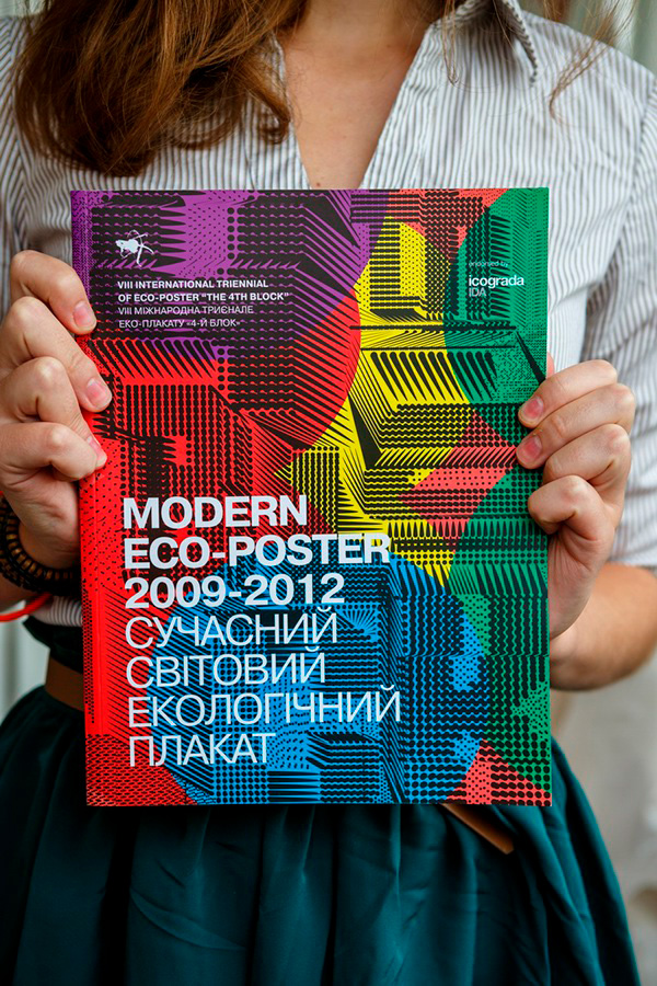 4th Block catalogue front cover. It uses rainbow-like colours the title is in large capital white bold letters, and shows a woman behind the cover holding it up