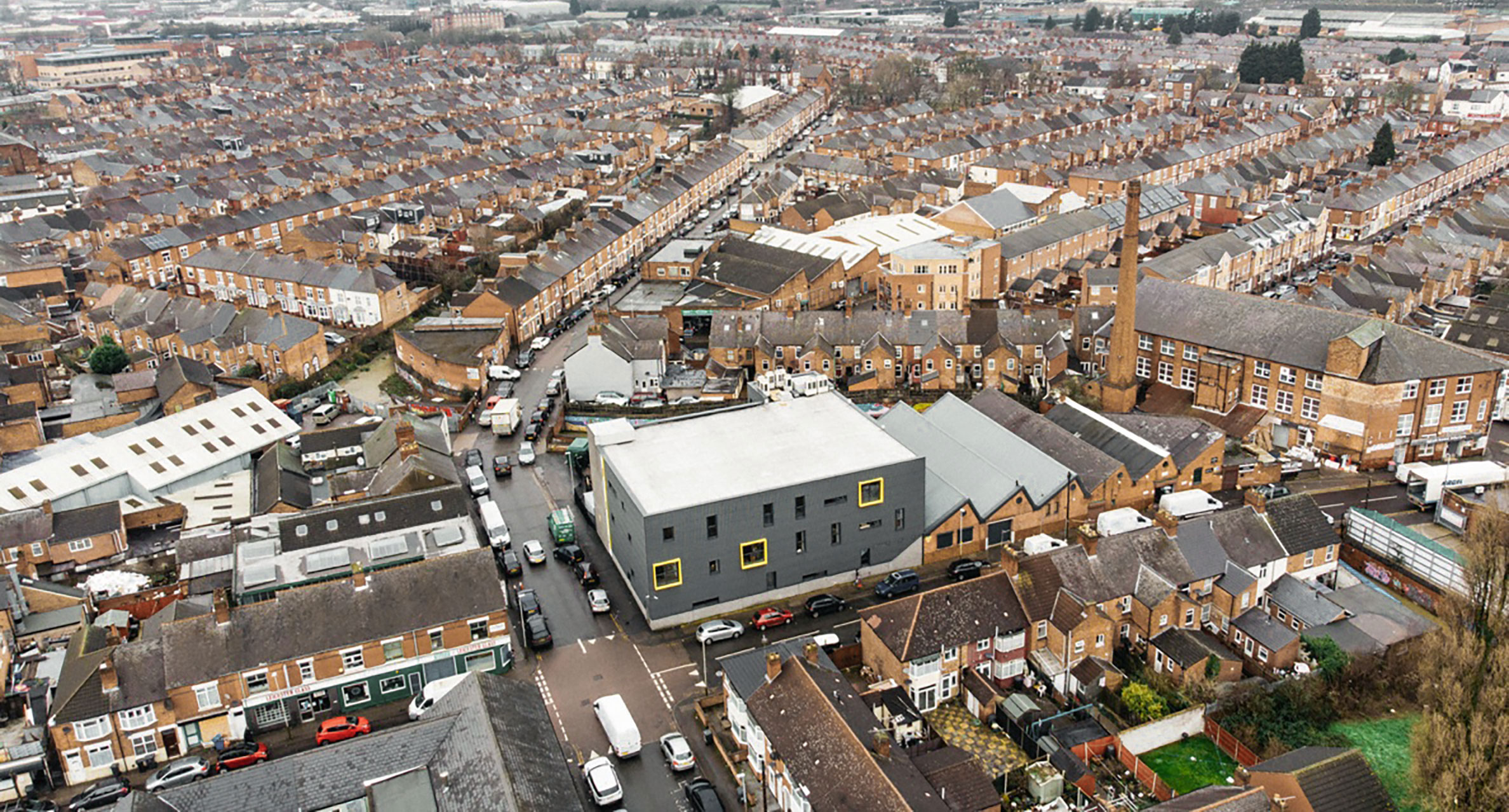 Aerial photograph out the factory and surrounding area, shows the top of many terraced house and other buildings, then the skyline at the far top