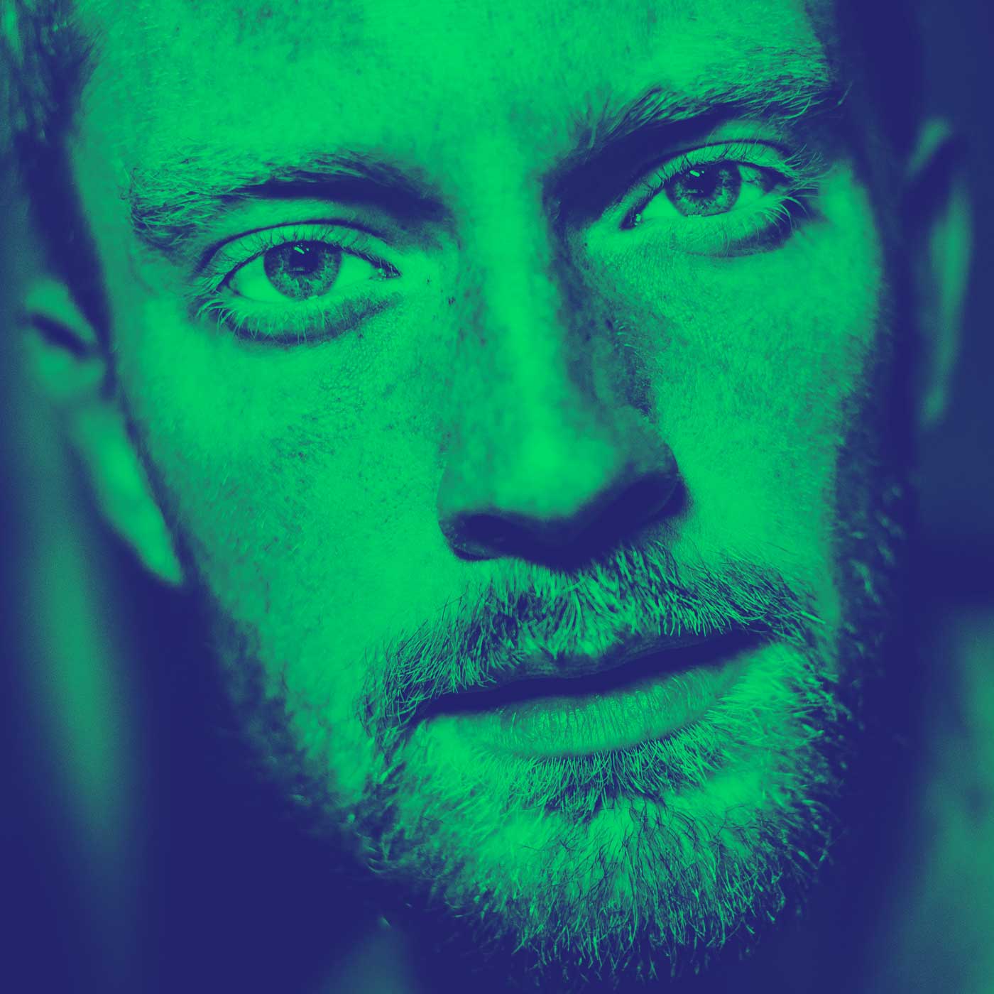 Photograph of a man's face in greyscale with a cool dark green over the top
