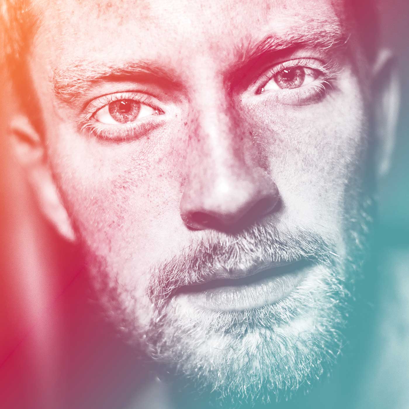 Photograph of a man's face with bright red and green gradient over the top of it, from left to right